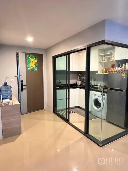 คอนโด ให้เช่า - ครัวปิดบานเลื่อนกระจก ตู้สีขาว เคาน์เตอร์ดำ พร้อมเครื่องซักผ้าในห้อง