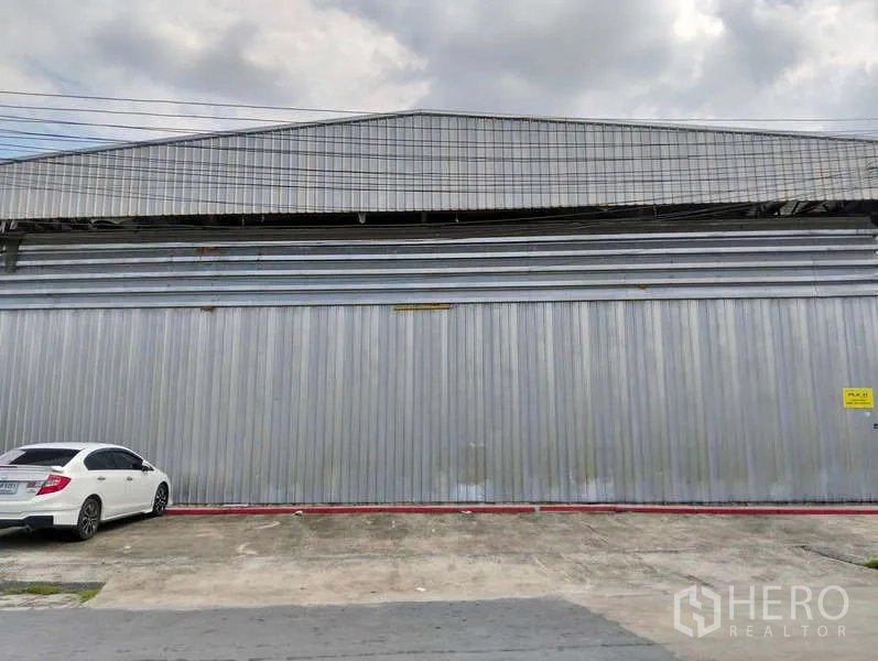 คลังสินค้า ให้เช่าในKhlong Sam Wa, Bangkok - ด้านหน้าโกดังบานสไลด์โลหะกว้าง พร้อมลานจอดรถด้านหน้า