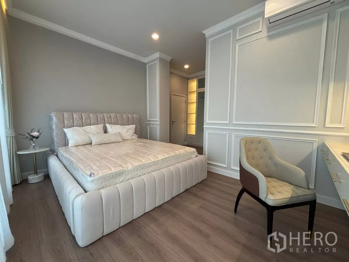 独立式住宅 出租在Bang Phli, Samut Prakan - 卧室内绗缝床、墙面线条与妆台椅。