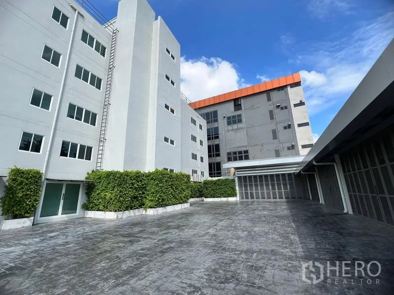 零售空间 出租在Huai Khwang, Bangkok - 现代低层建筑庭院，灰色外立面、绿篱与装卸门