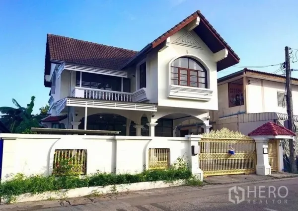 Detached House for rent in Khlong Toei, Bangkok - Two-storey detached house with gabled roof, white facade and gold gate behind a perimeter wall in Phra Khanong near BTS On Nut.
