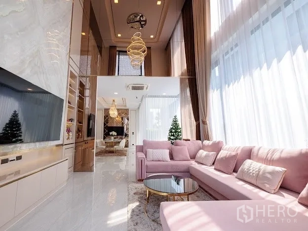 Detached House for sale in Prawet, Bangkok - Living area with floor-to-ceiling windows, chandelier, and open flow to dining space.