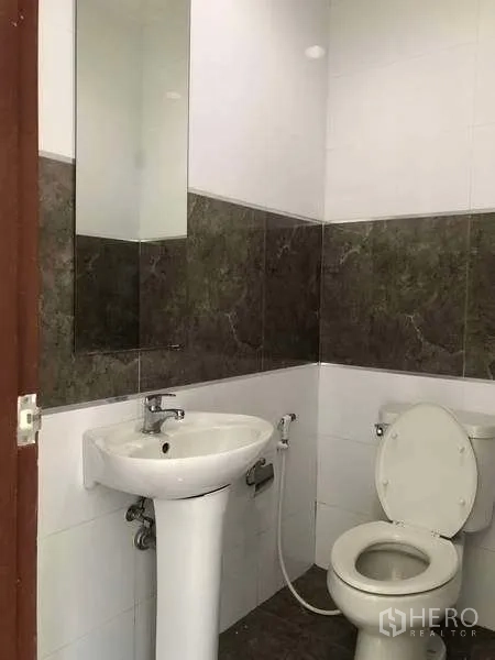 Factory for rent or sale in Bang Phli, Samut Prakan - Clean tiled restroom with pedestal sink, mirror and standard flush toilet.