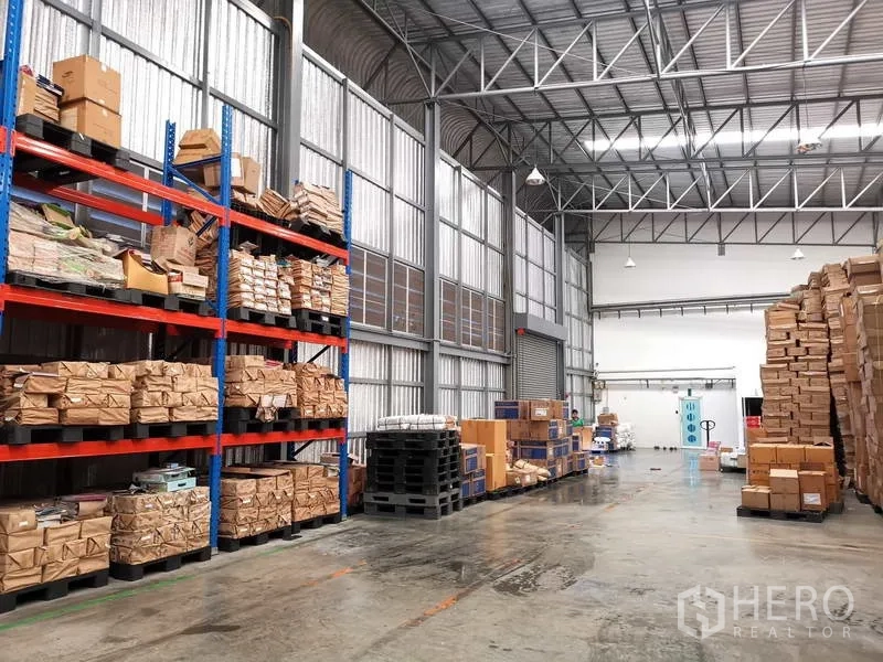 คลังสินค้า ให้เช่าหรือขายในNonthaburi - ภายในโกดังมีช่องแสง ประตูม้วน และพาเลทสินค้าเรียงข้างชั้นเหล็ก