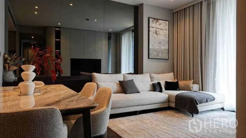 Condominium for rent or sale in Watthana, Bangkok - Stylish living-dining room with mirrored wall, sofa and marble dining table.