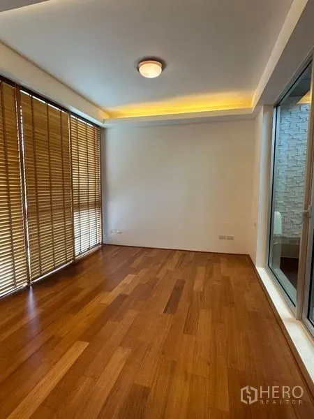 Townhouse for sale in Yan Nawa, Bangkok - Bedroom with wood flooring, cove lighting and large window with wooden blinds and balcony access