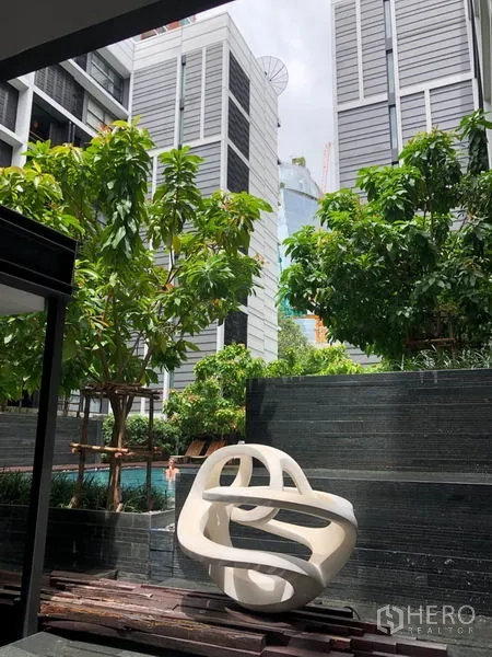 Condominium for rent in Watthana, Bangkok - Modern condominium courtyard with sculptural seating, greenery, and views toward the pool.