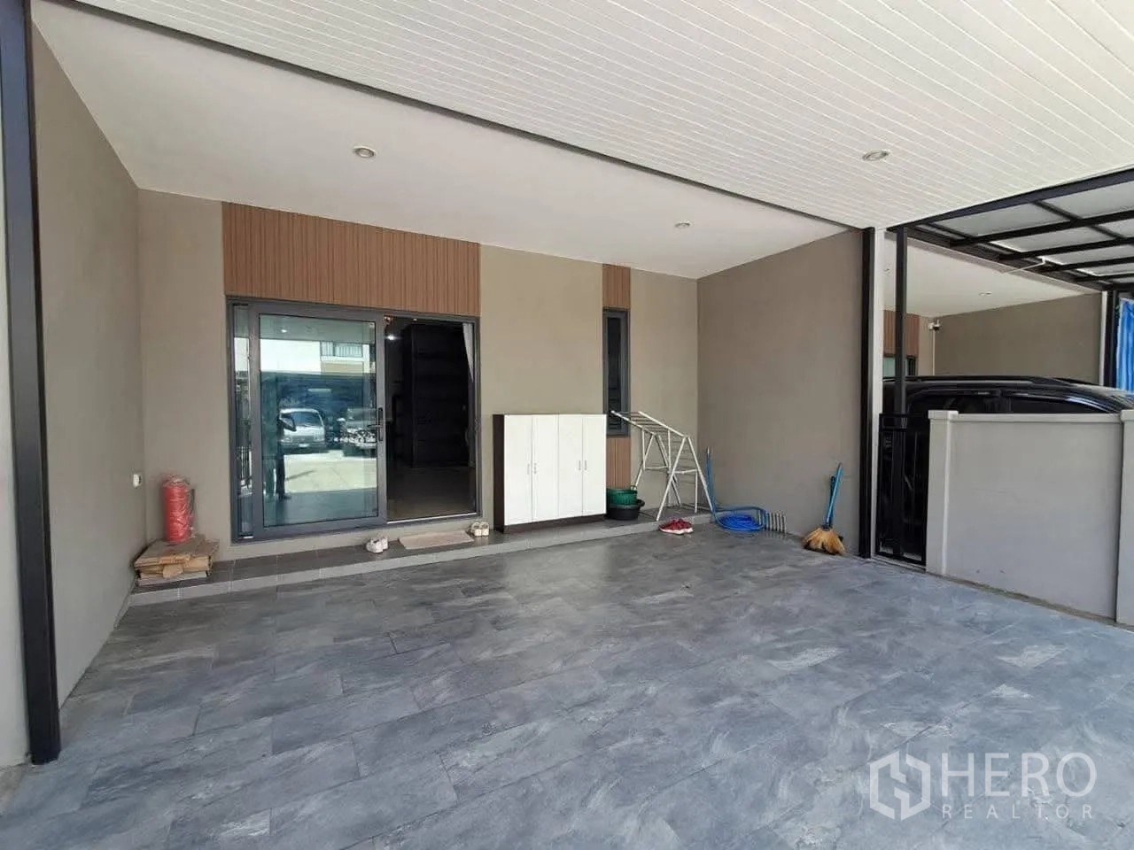 联排别墅 for rent in Bang Kapi, Bangkok - 带瓷砖地面与推拉玻璃门的顶棚车位，旁有收纳柜。