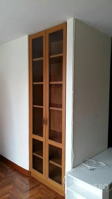 Condominium for rent in Watthana, Bangkok - Tall glass-front wooden cabinet beside a white TV console.