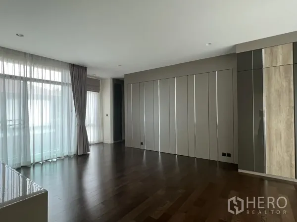 Detached House for rent or sale in Bang Kapi, Bangkok - Spacious upper-floor room with floor-to-ceiling windows, built-in wardrobes and wood floors.