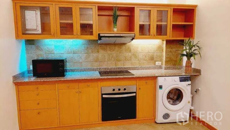 房间 出租 - 厨房台面带嵌入式烤箱、微波炉置位与洗衣机，温润木柜体。