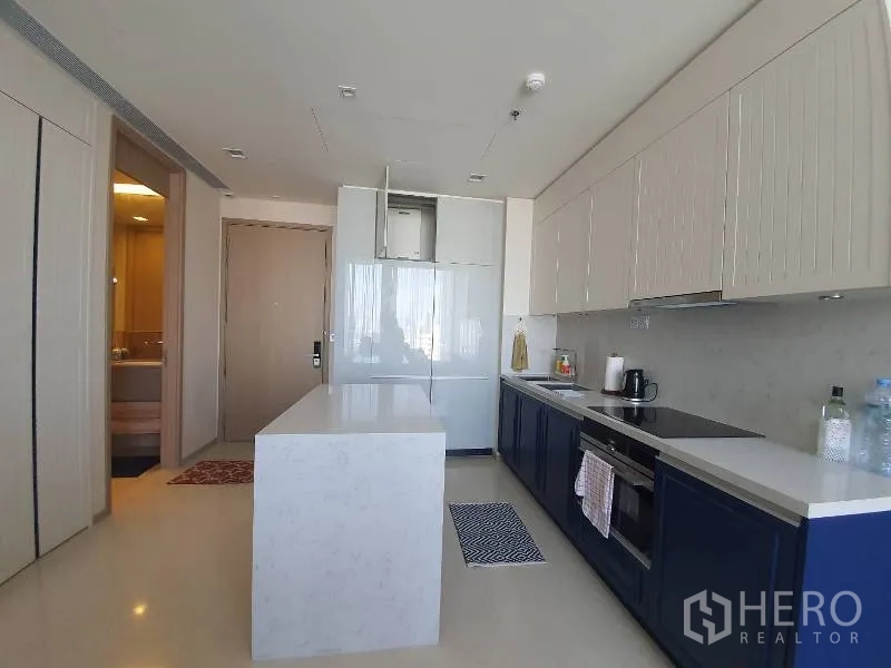 Condominium for rent or sale in Watthana, Bangkok - Modern kitchen with white island, full-height refrigerator, built-in oven and sleek cabinetry.
