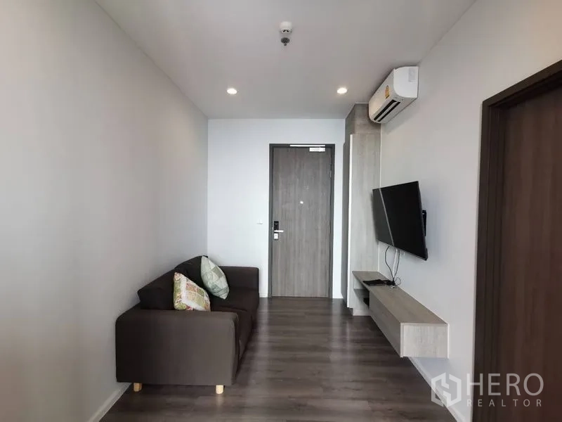 公寓 出售在Phra Khanong, Bangkok - 明亮客厅，配沙发、壁挂电视、空调与木地板。