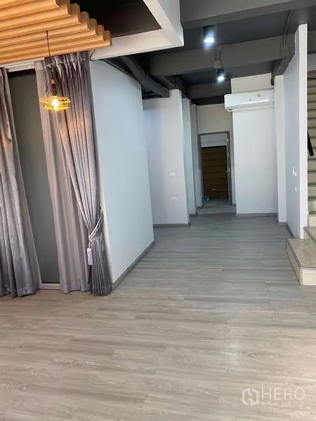 Home Office for rent or sale - Open room with decorative wood-slat ceiling, pendant lamps, grey curtains and stairs.