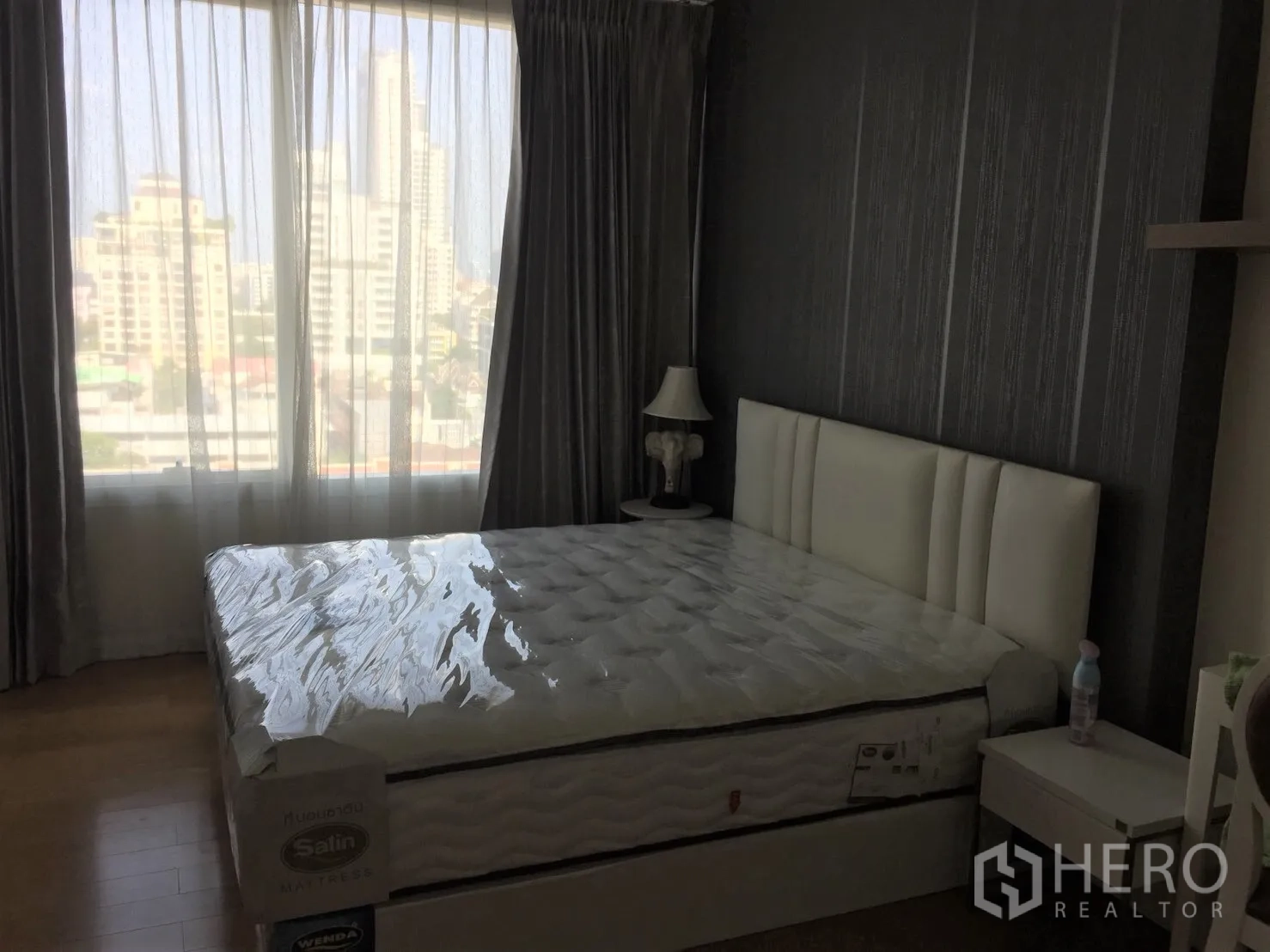 คอนโด ให้เช่าในWatthana, Bangkok - ห้องนอนวิวเมือง ม่านโปร่ง โต๊ะข้างเตียง และพื้นไม้โทนอุ่น