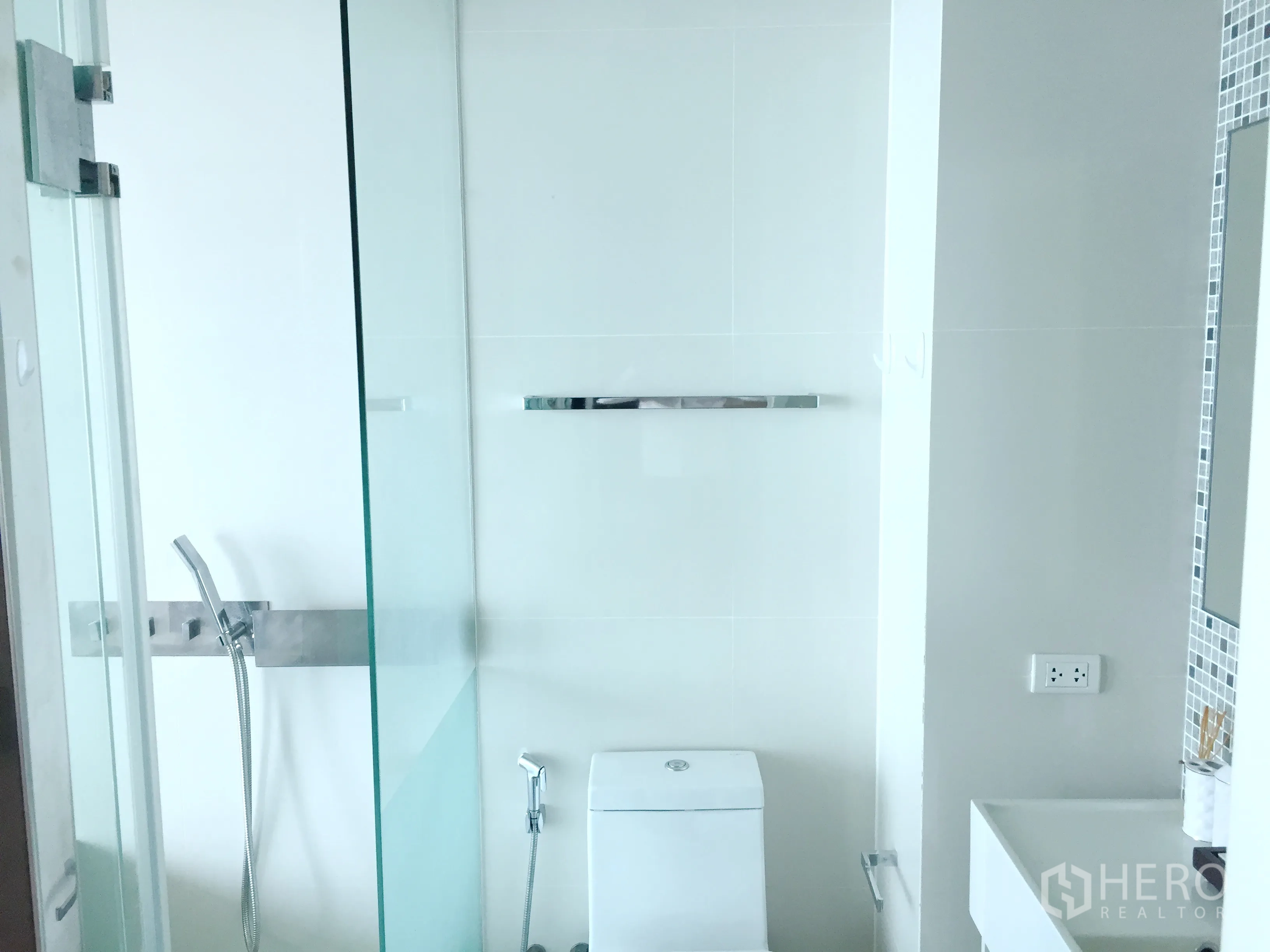 公寓 出租或出售在Watthana, Bangkok - 现代白色卫浴，玻璃淋浴间、手持花洒与洗手台。