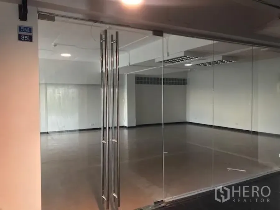 Office Space for rent in Watthana, Bangkok - Glass-walled entrance opening to a spacious open-plan office with ceiling lights.