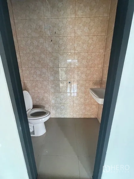 Warehouse for rent in Bang Kapi, Bangkok - Tiled restroom with toilet and wall-mounted sink inside the warehouse facility.