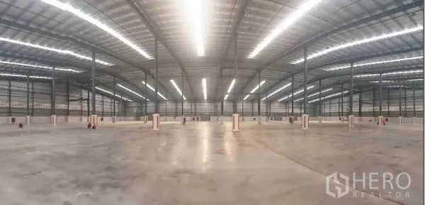 工厂 出租在Mueang Rayong, Rayong - 宽阔仓库地面全景，线性灯带明亮，钢柱网格排布。