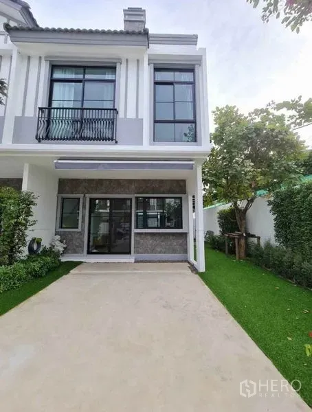 ทาวน์เฮาส์ ให้เช่าในBang Phli, Samut Prakan - ด้านหน้าทาวน์เฮ้าส์สองชั้น ลานจอดรถ หน้าต่างบานใหญ่ และสวนแต่งสวย