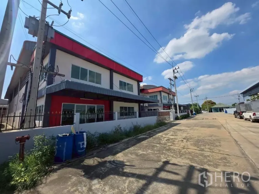 โรงงาน ให้เช่าหรือขายในMueang Samut Sakhon, Samut Sakhon - ภาพด้านหน้าโรงงานสองชั้นดีไซน์โมเดิร์น โทนแดง รั้วรอบขอบชิด และถนนทางเข้า-ออกกว้างในสมุทรสาคร