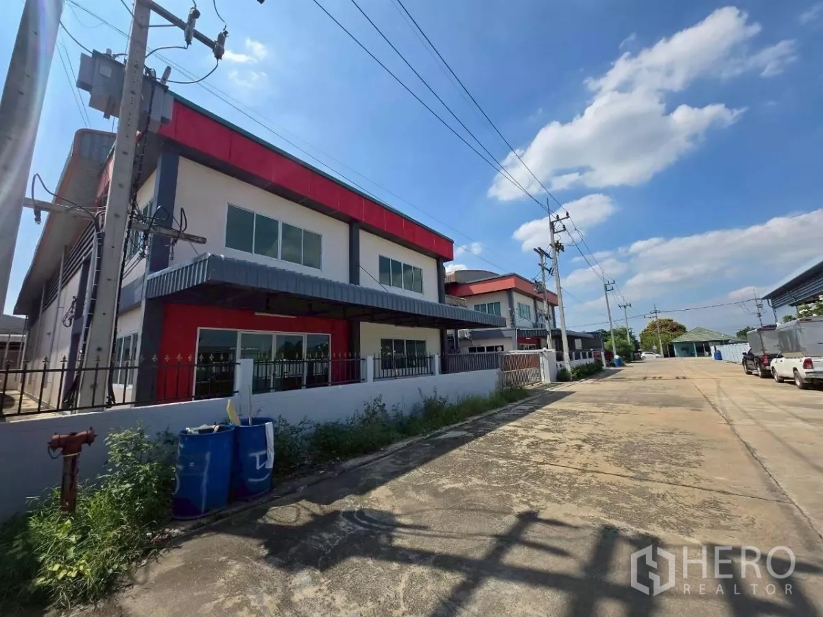 โรงงาน ให้เช่าหรือขายในMueang Samut Sakhon, Samut Sakhon - ภาพด้านหน้าโรงงานสองชั้นดีไซน์โมเดิร์น โทนแดง รั้วรอบขอบชิด และถนนทางเข้า-ออกกว้างในสมุทรสาคร