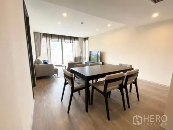 Condominium for rent in Pathum Wan, Bangkok - Open-plan living and dining room with six-seat table, sofa set, and floor-to-ceiling windows to the balcony.