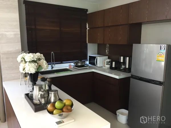 Detached House for sale in Prawet, Bangkok - Contemporary U-shaped kitchen with wood cabinets, island counter and stainless appliances.