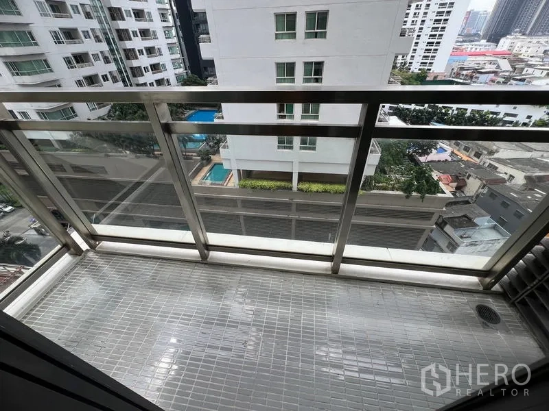 公寓 出租在Khlong Toei, Bangkok - 玻璃栏杆阳台俯瞰周边高楼与下方泳池景观。