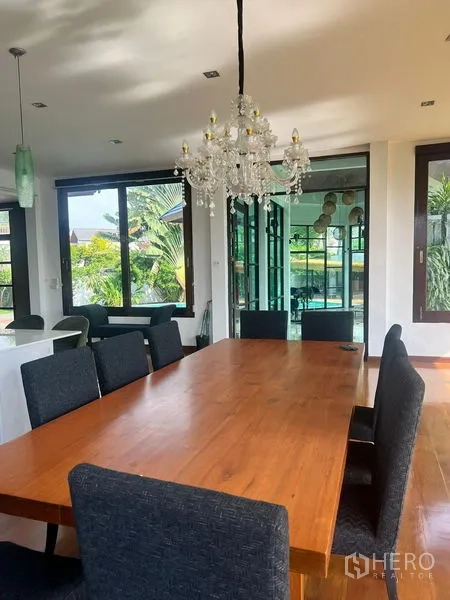 Detached House for sale in Prawet, Bangkok - Bright dining room with long wooden table, upholstered chairs, and chandelier.