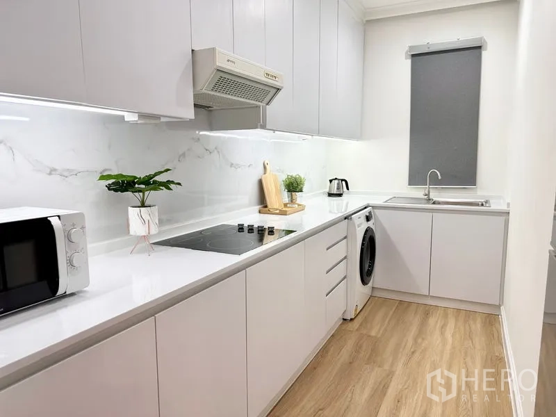 คอนโด ให้เช่าในKhlong San, Bangkok - ครัวปิดโทนขาว บัคสเปลชลายหินอ่อน เตาไฟฟ้า เครื่องซักผ้า และตู้เก็บของจำนวนมาก