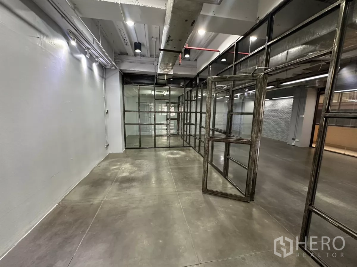 办公空间 出租 - 狭长房间，旋转玻璃门与外露管线天花。