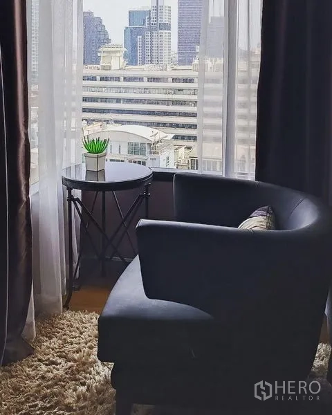 公寓 出售在Bang Rak, Bangkok - 窗边阅读角，扶手椅、小边几与长绒地毯。