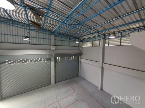 Warehouse for rent in Suan Luang, Bangkok - High-ceiling warehouse interior with steel trusses and three roller doors.