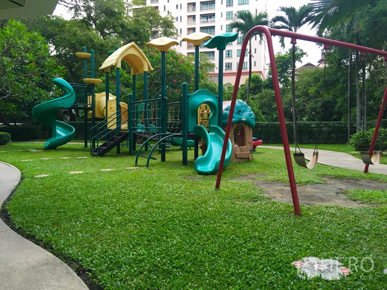 公寓 出租或出售在Watthana, Bangkok - 葱郁花园中的儿童游乐场，设有秋千与滑梯。