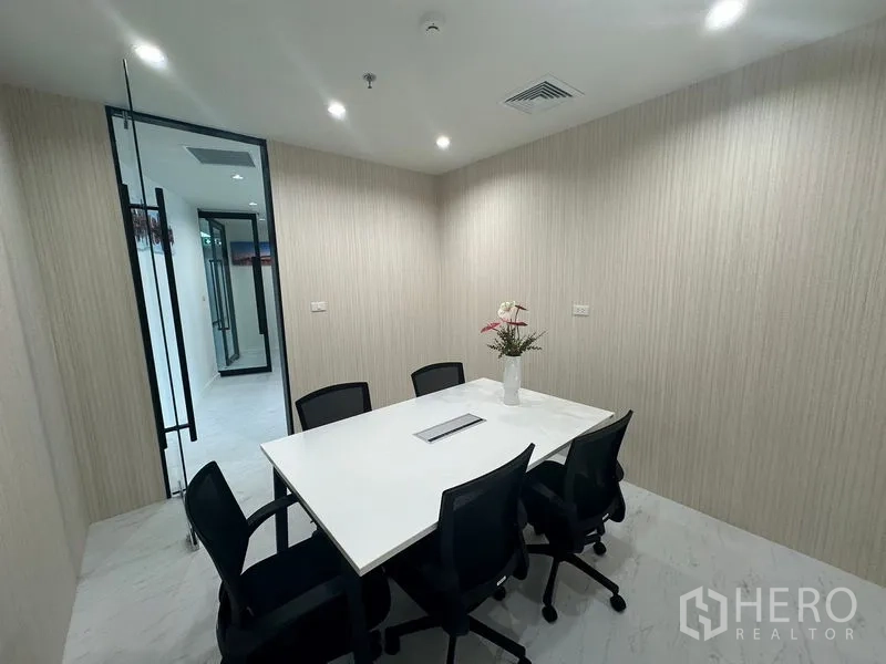 Office Space for rent - Conference room view with white table for six, soft lighting and neutral walls.