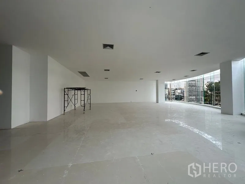 零售空间 出租在Din Daeng, Bangkok - 明亮白色毛坯店面，弧形玻璃立面，天花送风口与脚手架，待装潢。