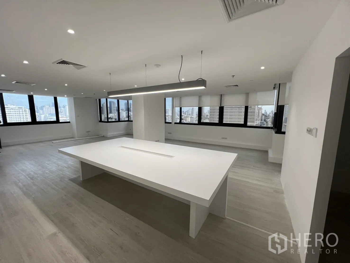 Office Space for rent in Khlong Toei, Bangkok - Wide shot of open‑plan office showing an island workstation and skyline views through expansive windows.