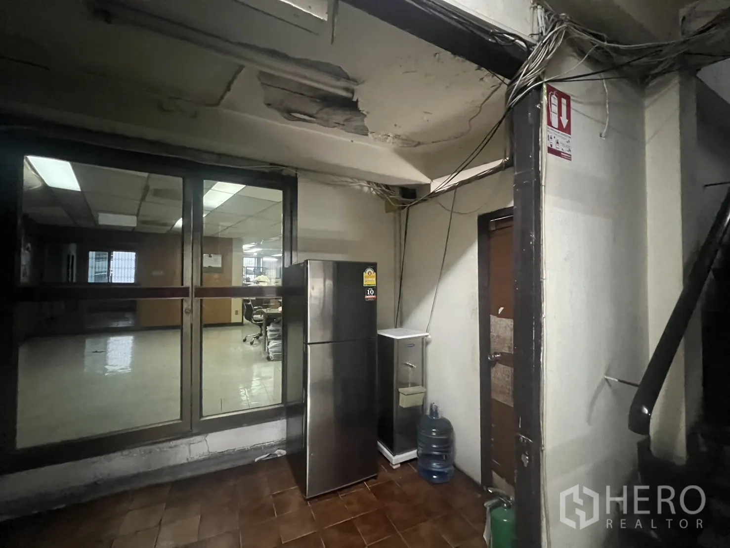 อาคารพาณิชย์ ให้เช่า - โซนบริการด้านหลังมีประตูกระจก ตู้เย็น และฝ้าเพดานเดินสายไฟ.
