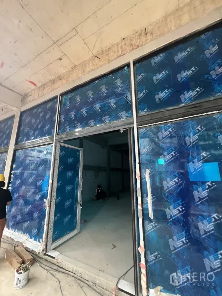 零售空间 出租在Khlong Toei, Bangkok - 毛坯零售铺面，落地玻璃门面正在安装。