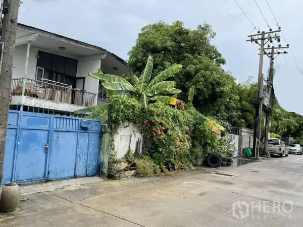 Detached House for sale in Khlong Toei, Bangkok - Two-storey detached house with balcony, blue metal gate and lush vines on a quiet Phra Khanong lane.