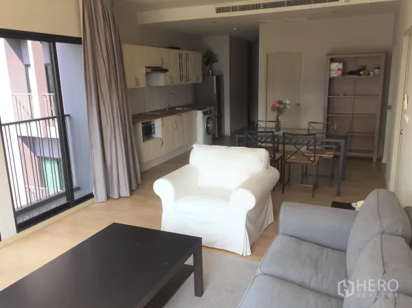 公寓 出租或出售在Watthana, Bangkok - 明亮的开放式客厅，落地阳台门、浅色木地板与一体化厨房。