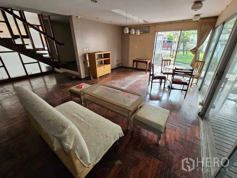 บ้าน ให้เช่าในSathon, Bangkok - พื้นที่นั่งเล่นชั้นล่างมีบันไดและวิวสวนผ่านหน้าต่างบานใหญ่