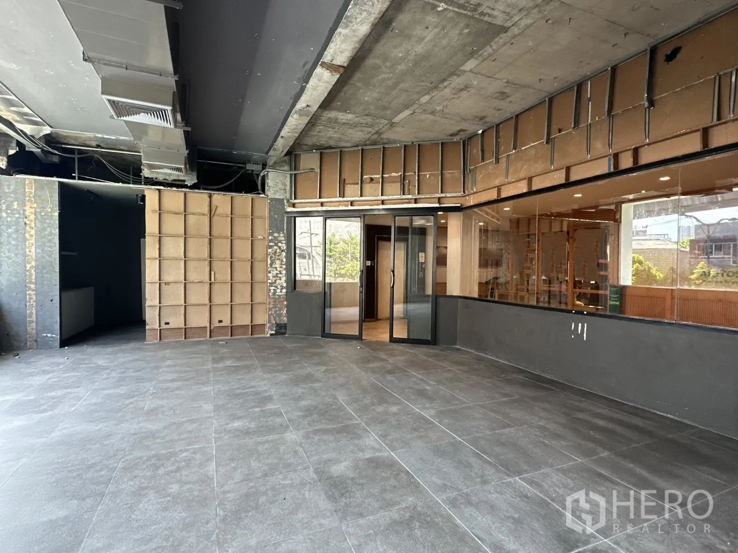 Retail Space for rent in Watthana, Bangkok - Spacious open-plan retail hall with gray tiles and exposed ceiling ducts.