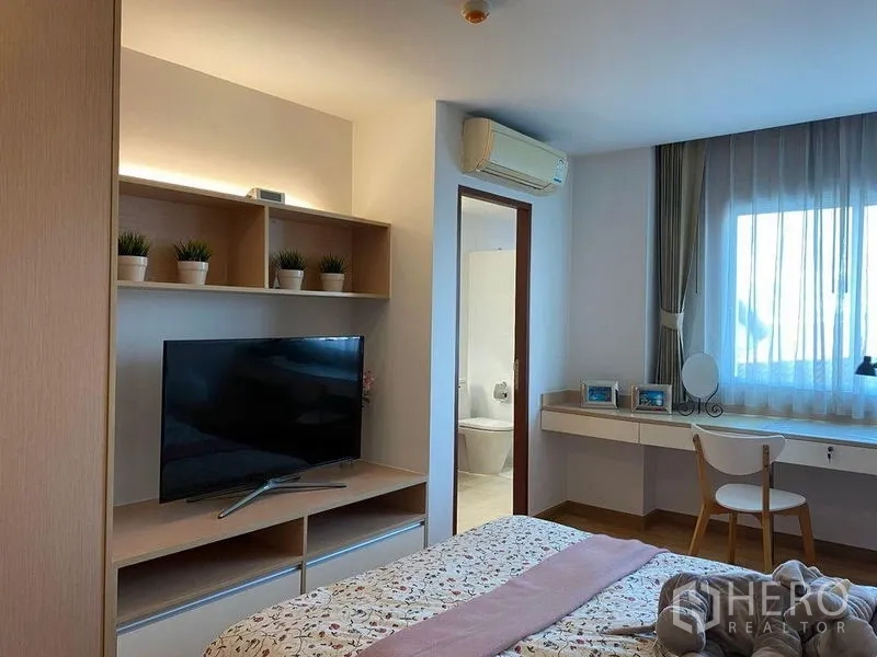 คอนโด ให้เช่าหรือขายในPhra Khanong, Bangkok - ห้องนอนพร้อมชั้นวางและทีวี ประตูเข้าสู่ห้องน้ำ และโต๊ะริมหน้าต่าง