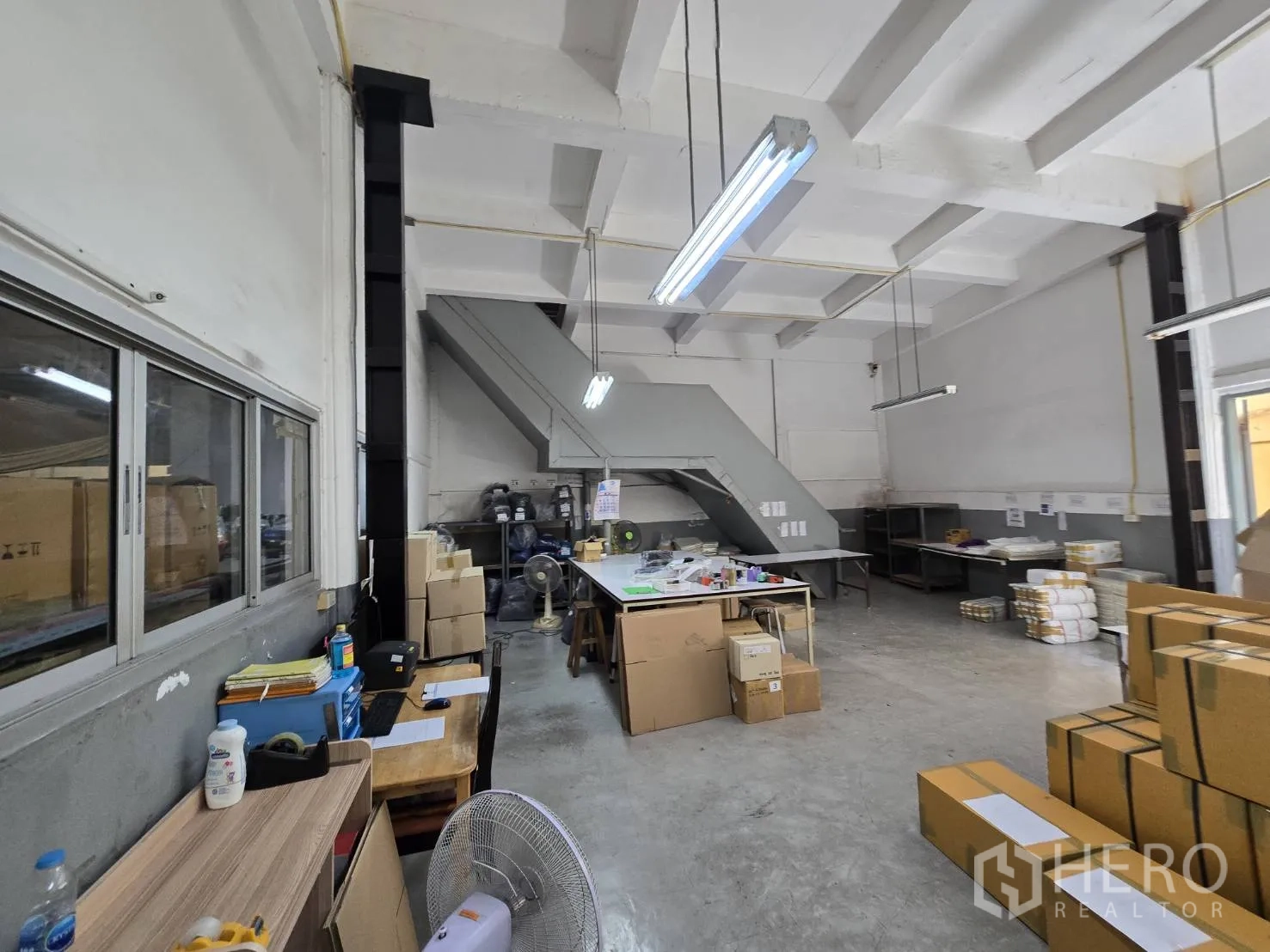 Factory for rent in Sam Phran, Nakhon Pathom - Packing and preparation area with tables, boxes, and stair access.