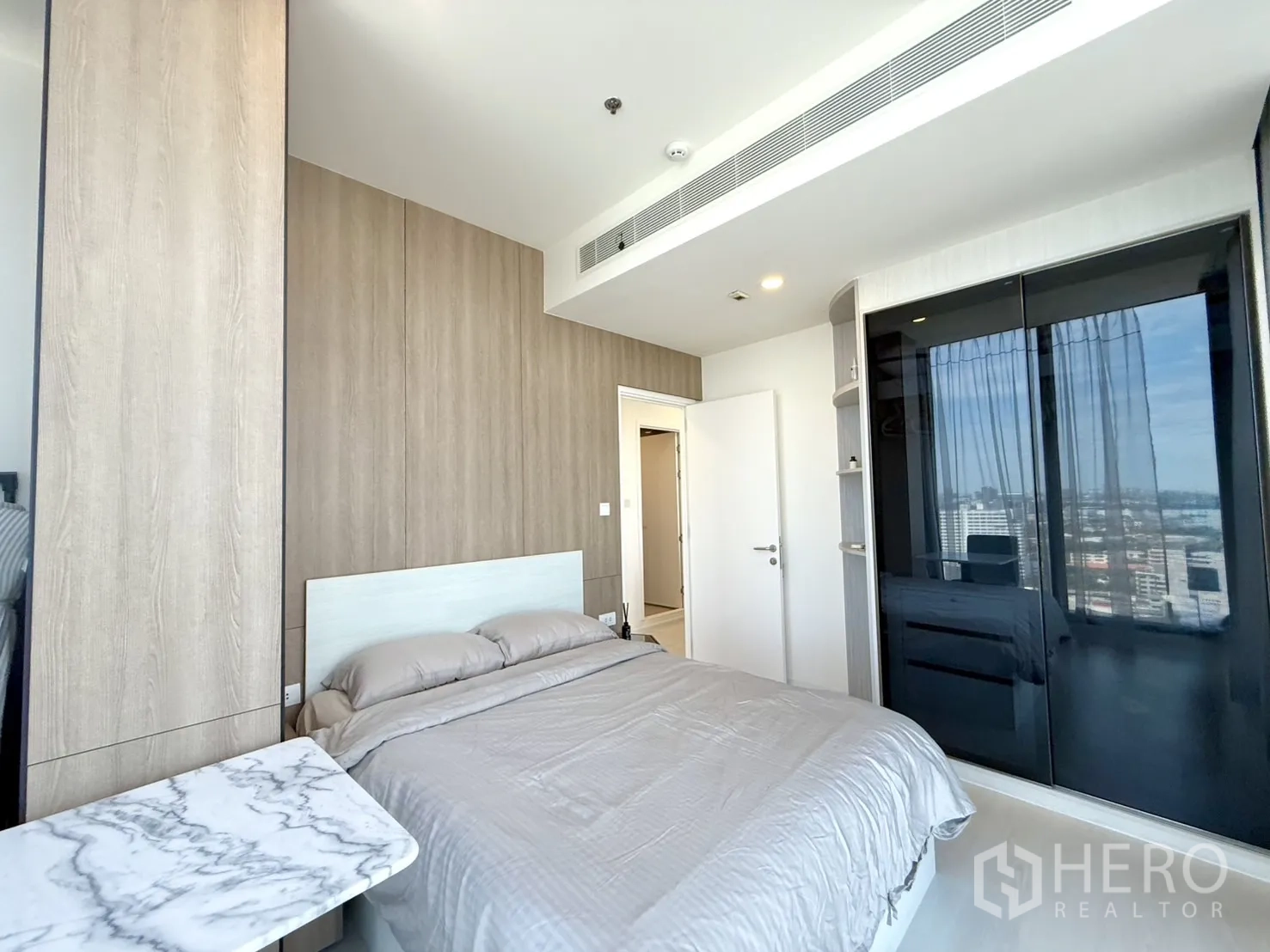Condominium for sale in Chatuchak, Bangkok - Bedroom with wood wall panels, bed, and glossy built-in wardrobe.