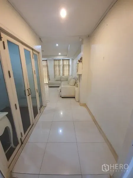 Townhouse for rent in Phaya Thai, Bangkok - Hallway with glass doors, white tiled floor and soft ceiling lights leading to the living area.