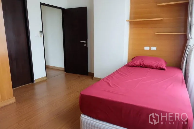Condominium for rent in Khlong Toei, Bangkok - Bright secondary bedroom with single bed, wood flooring, built-in shelves and large window
