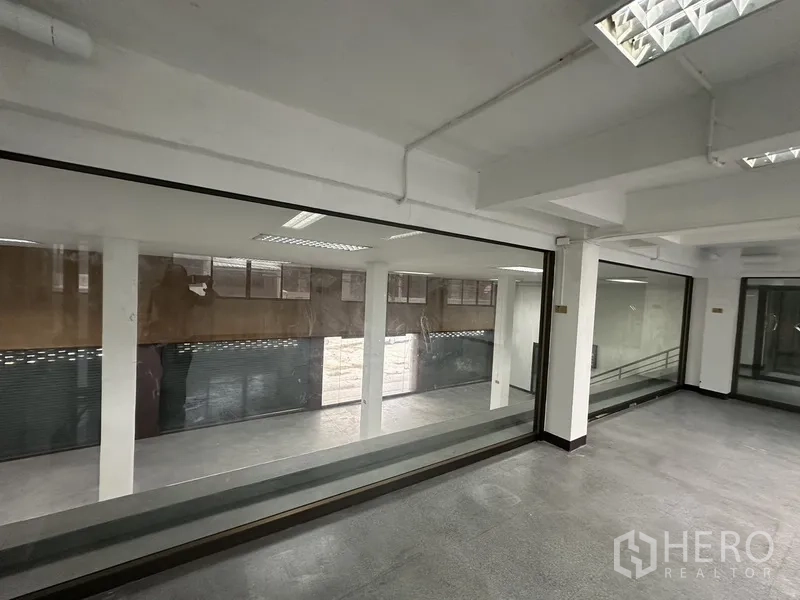 Office Space for rent in Khlong Toei, Bangkok - Internal picture window overlooking a lower level with columns and roller shutters.